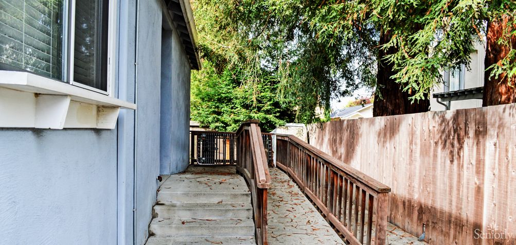 An outdoor pathway with a wooden ramp and stairs alongside a building.