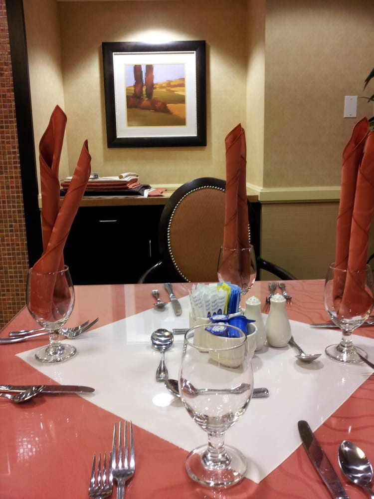 A formal dining table set with intricately folded napkins, glassware, and cutlery.