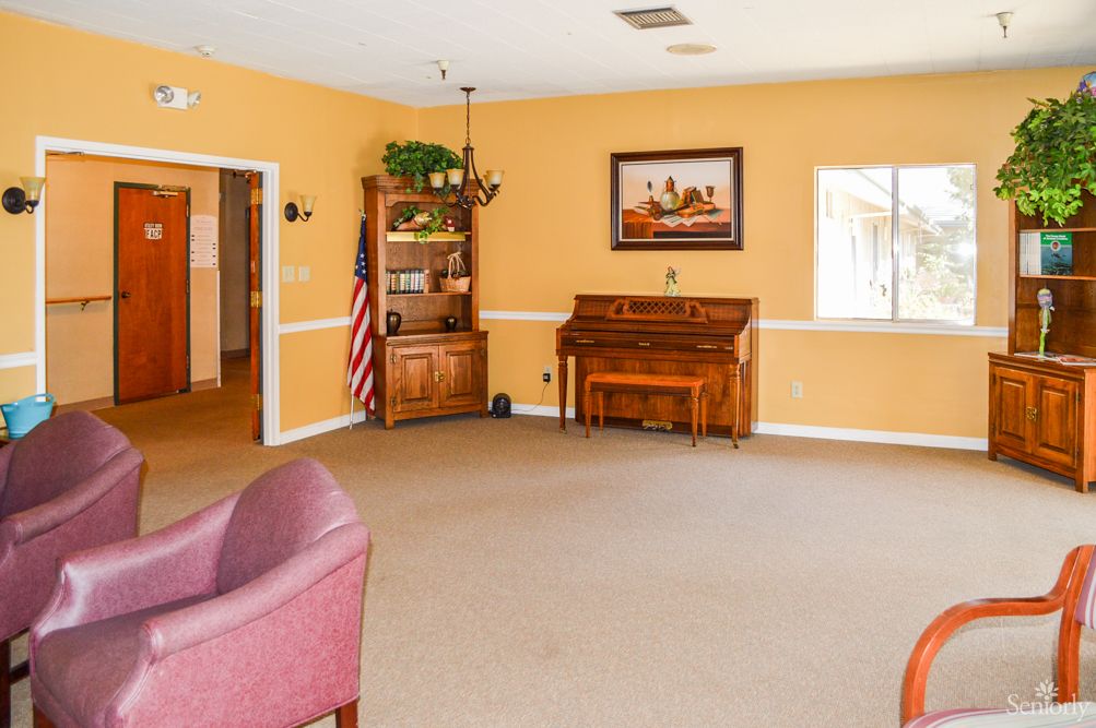 A spacious living room with yellow walls, featuring a piano and comfortable seating.