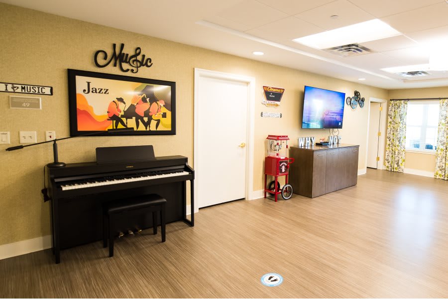 A cozy lounge area with a piano and a jazz-themed poster on the wall.