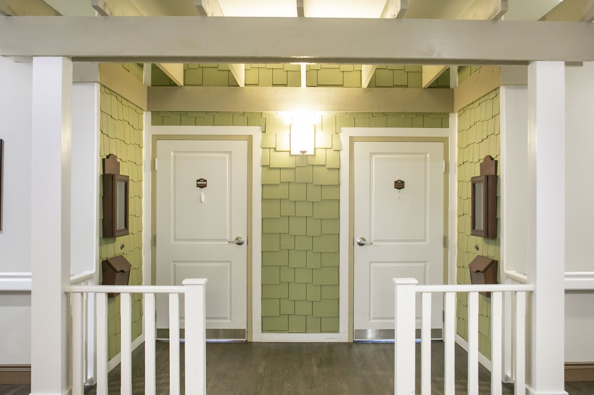 Two adjacent doors in a well-lit interior hallway with green walls.