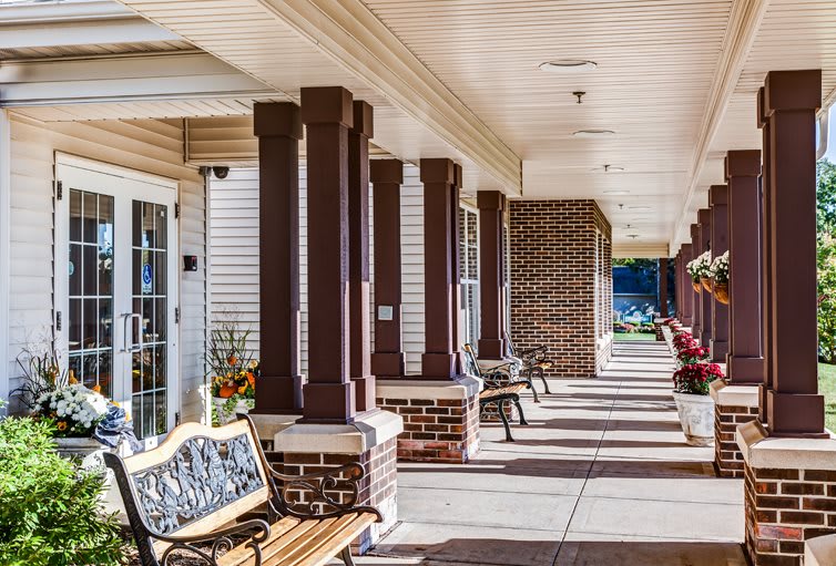 A sunlit veranda with benches and columns along a walkway.