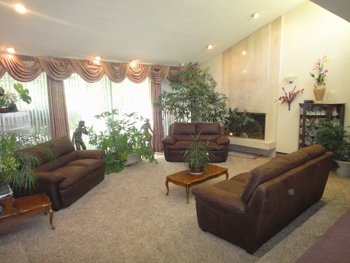 A cozy living room featuring brown sofas, indoor plants, and a fireplace.