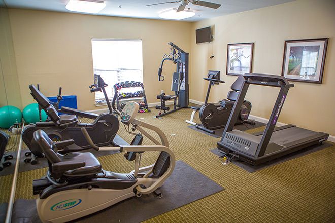 A small gym with various exercise equipment including treadmills, a stationary bike, and weight machines.