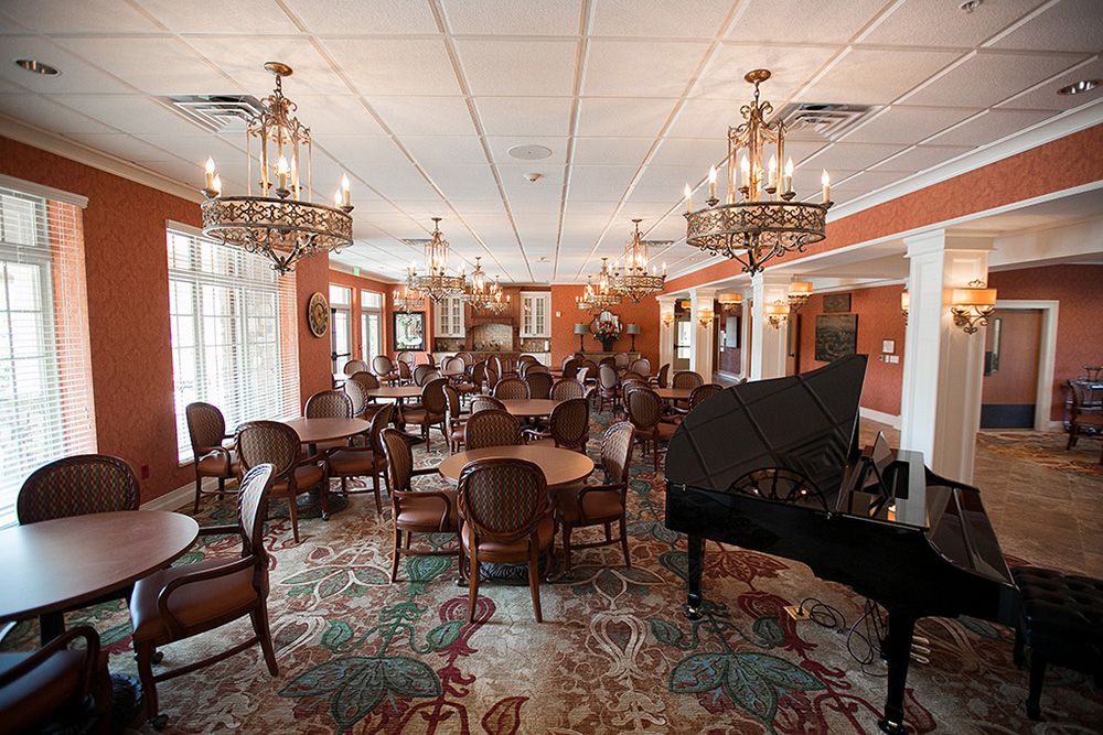 A luxurious dining room with chandeliers, elegant seating, and a grand piano.
