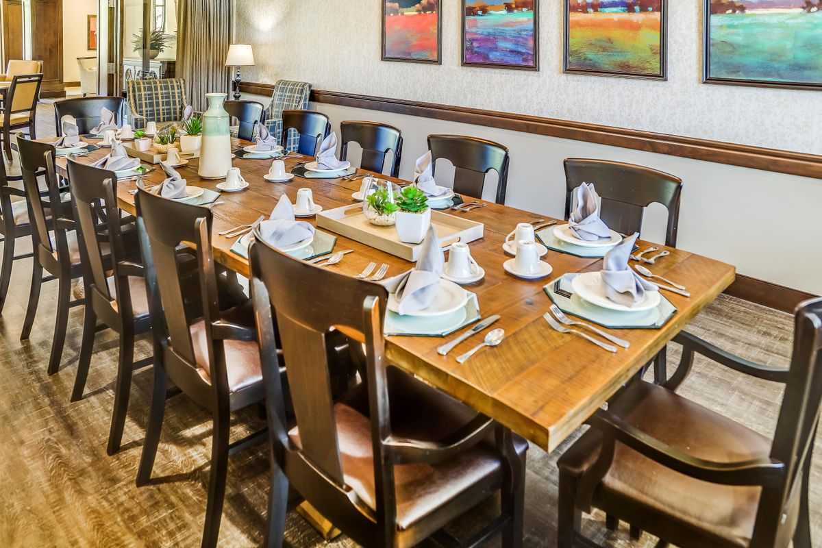 An elegantly set dining table ready for a meal, featuring neatly arranged chairs and tasteful decor.
