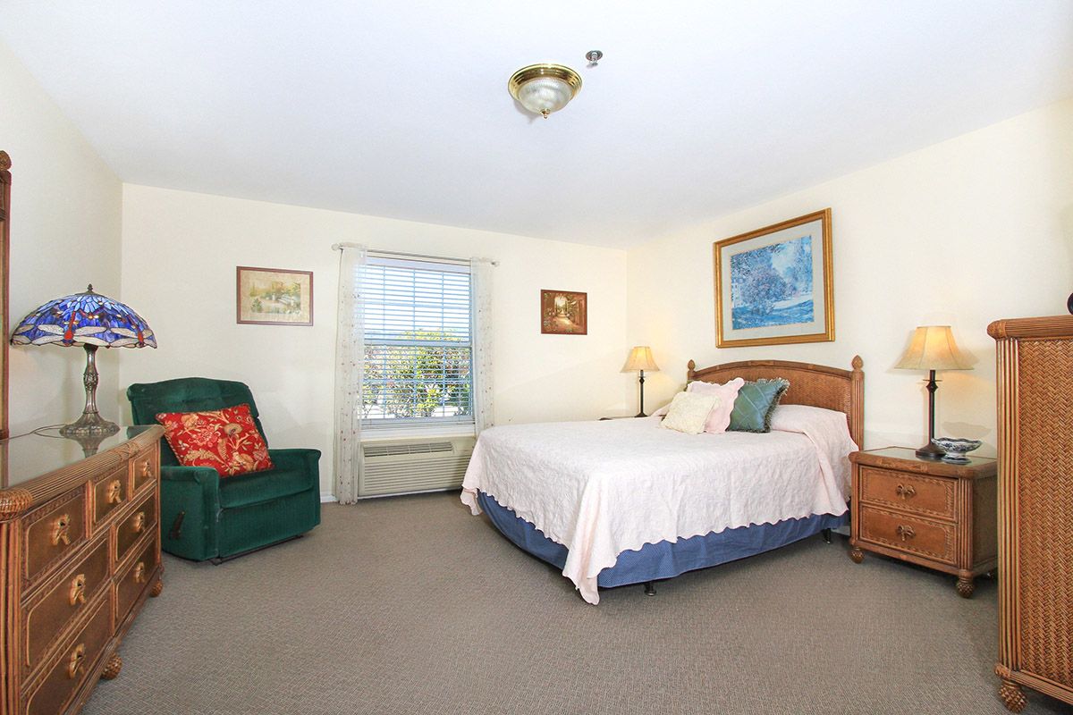 A cozy bedroom with a large bed, a green armchair, and decorative wall art.
