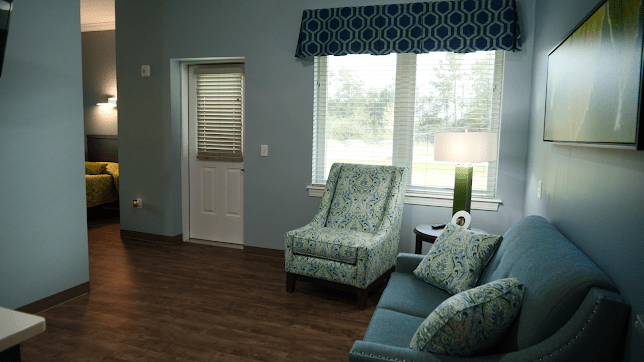 A cozy living room with patterned furniture and large windows.
