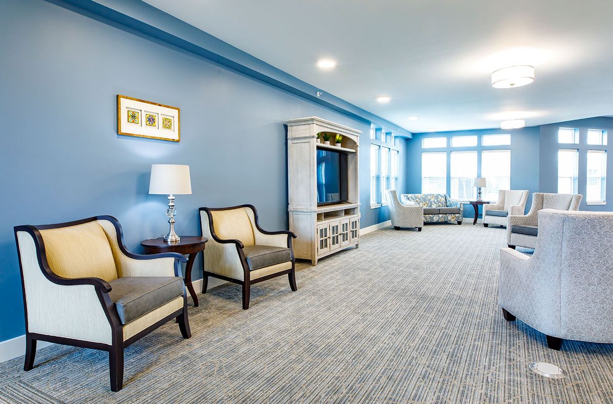 A spacious living room with blue walls and elegant furnishings, featuring a large television and ample seating.