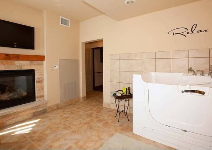 A spacious bathroom featuring a bathtub, fireplace, and tile flooring.