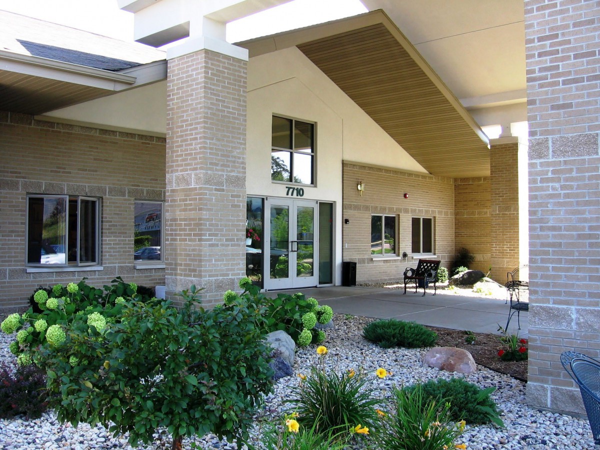Entrance of a modern building with landscaping and gardens.