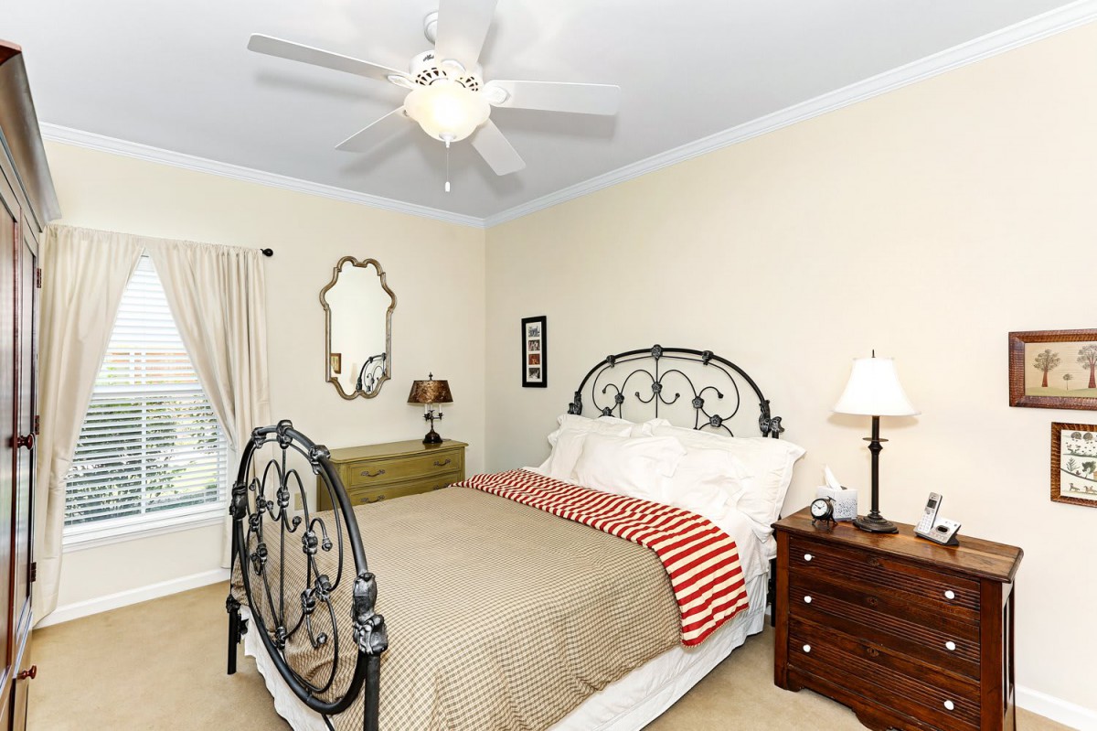 A cozy bedroom with a metal bed frame, ceiling fan, and bedside lamps.