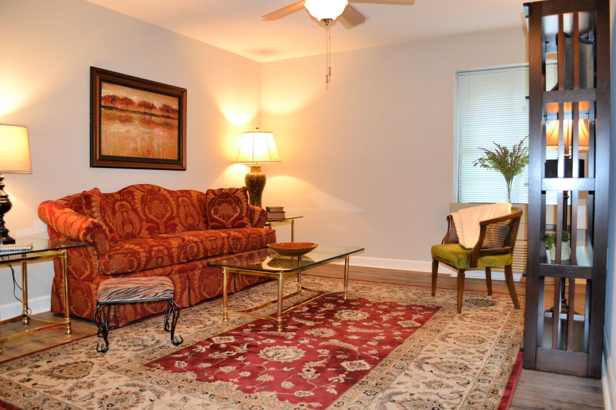 A cozy living room with a patterned sofa, glass coffee table, and elegant lighting.