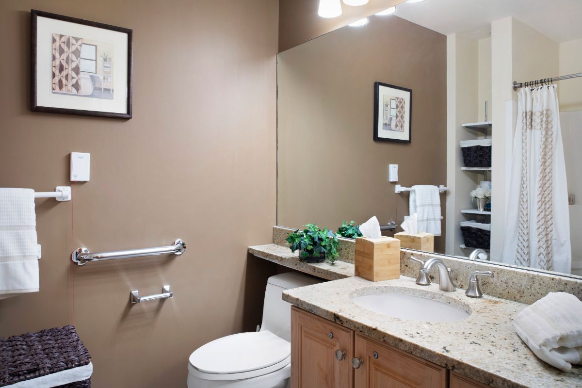 A well-organized bathroom featuring a sink, toilet, and mirror with decorative elements.