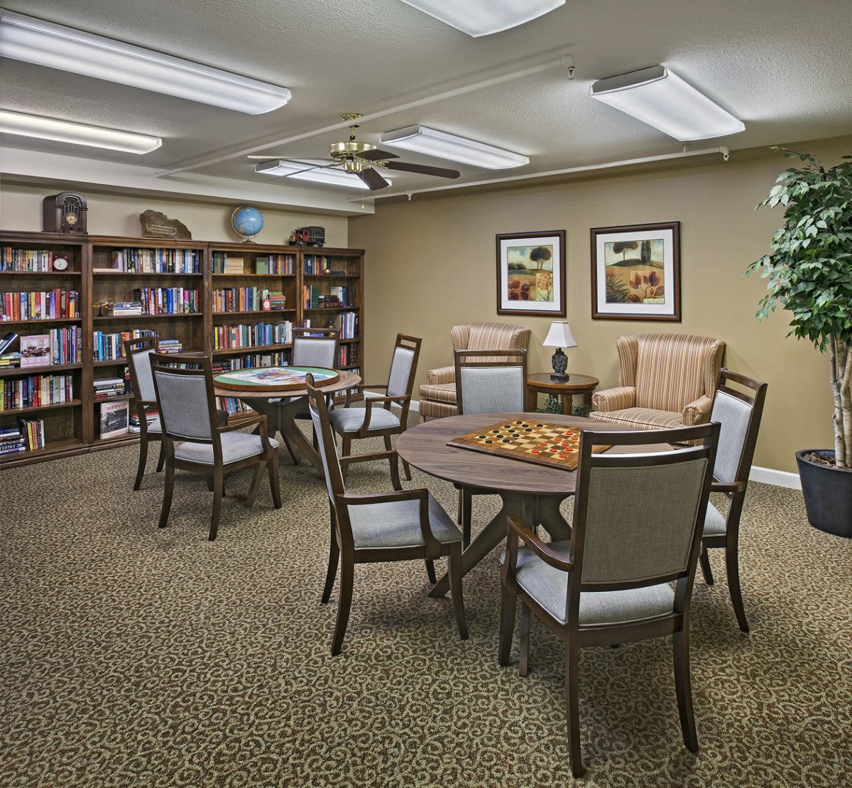 A cozy library reading room with several tables and chairs surrounded by bookshelves.