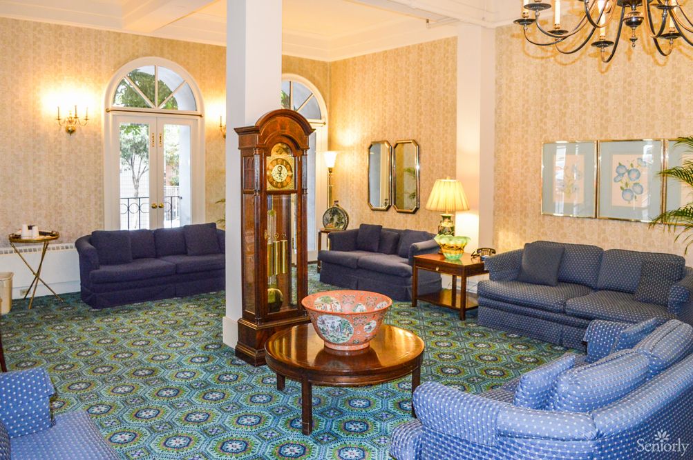 A cozy lobby area featuring blue sofas, a grandfather clock, and elegant decor.