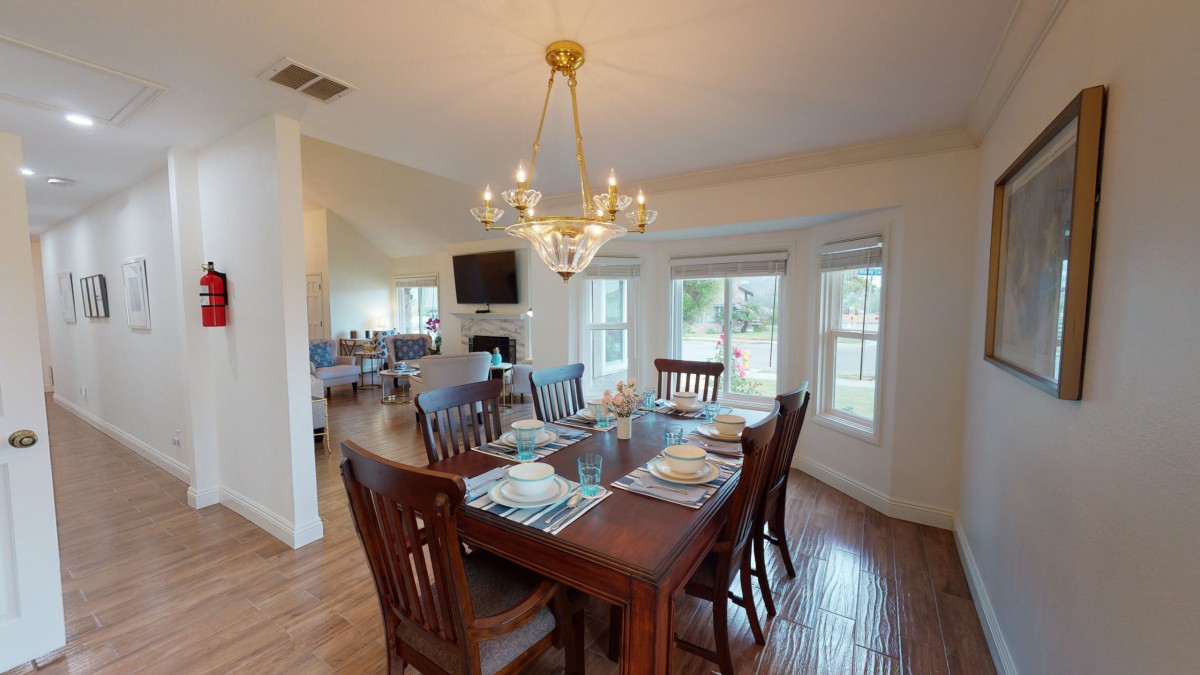 A beautifully set dining room with a large wooden table and chandelier.