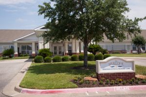 A well-maintained building with a front lawn featuring landscaping and a sign.