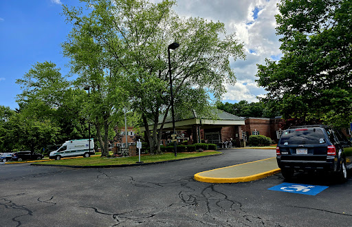 A welcoming entrance to a building surrounded by greenery under a cloudy sky.