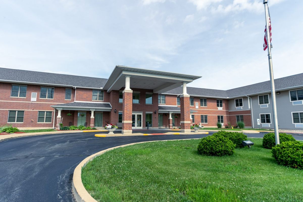 A large brick building with an extended front entrance and a circular driveway.
