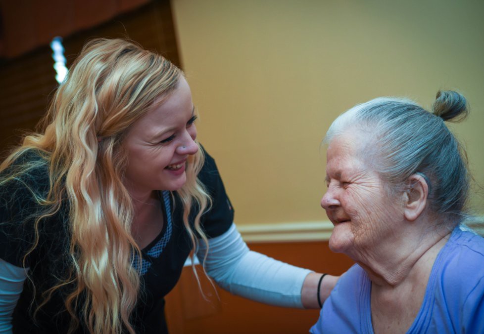 A caregiver and an elderly woman sharing a warm moment together.