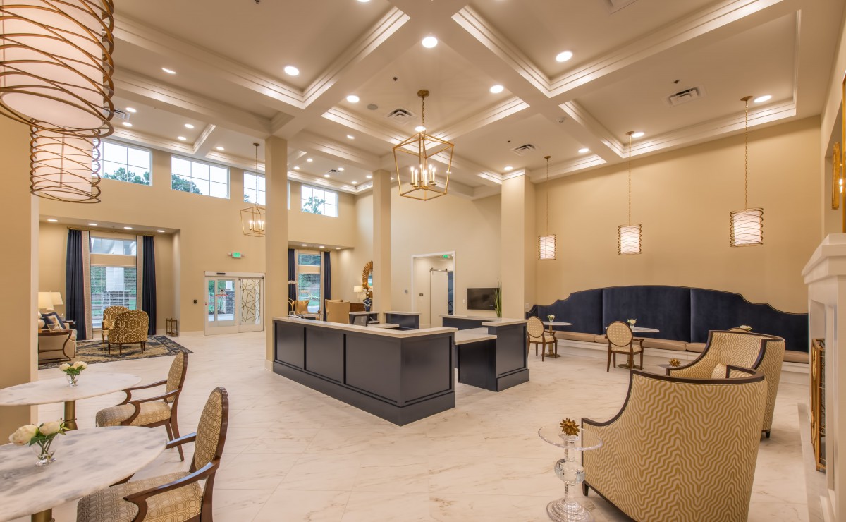 A spacious and modern lobby with a high ceiling, featuring comfortable seating and a central reception desk.