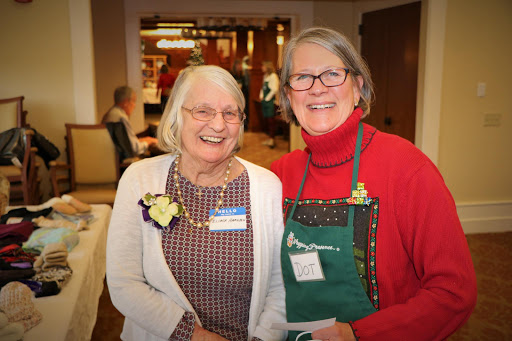 Two cheerful women pose together at a lively event.