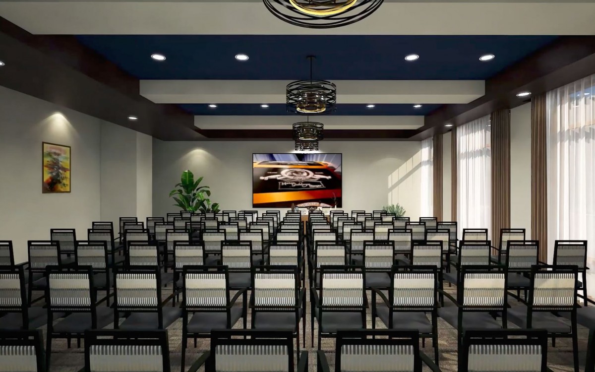An empty conference room with rows of chairs facing a presentation screen.
