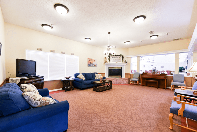 A spacious and brightly lit living room featuring comfortable blue sofas, a fireplace, and a coffee table.