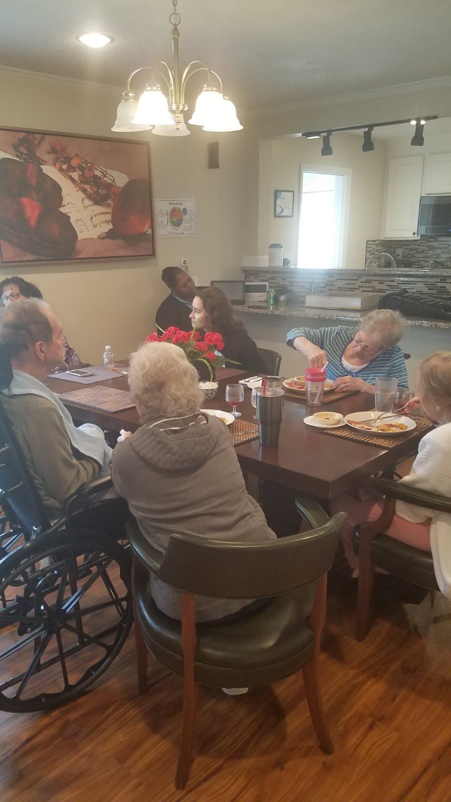 A group of elderly individuals sitting around a dining table, engaging in conversation.