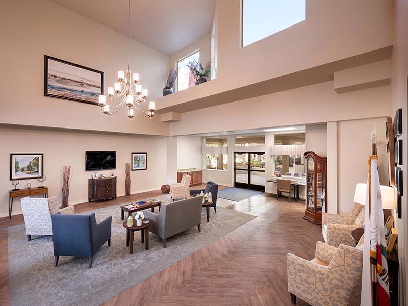 A spacious and modern living room with high ceilings, elegant furnishings, and a large chandelier.
