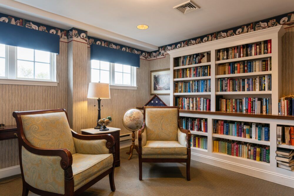 A cozy library space with bookshelves, armchairs, and a globe.