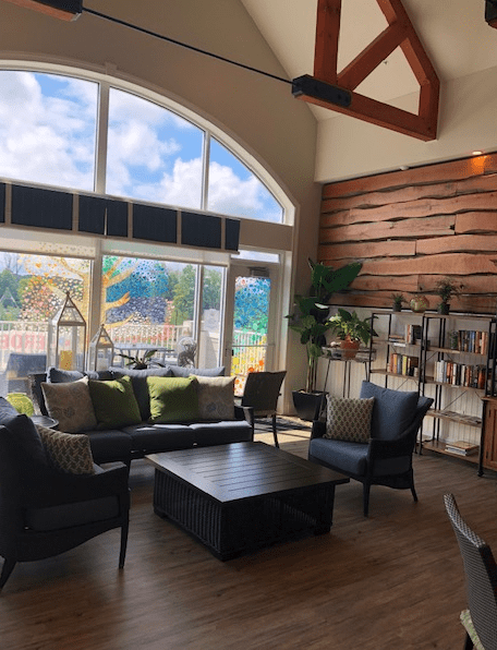 A modern living room with large windows, natural light, and stylish wooden accents.