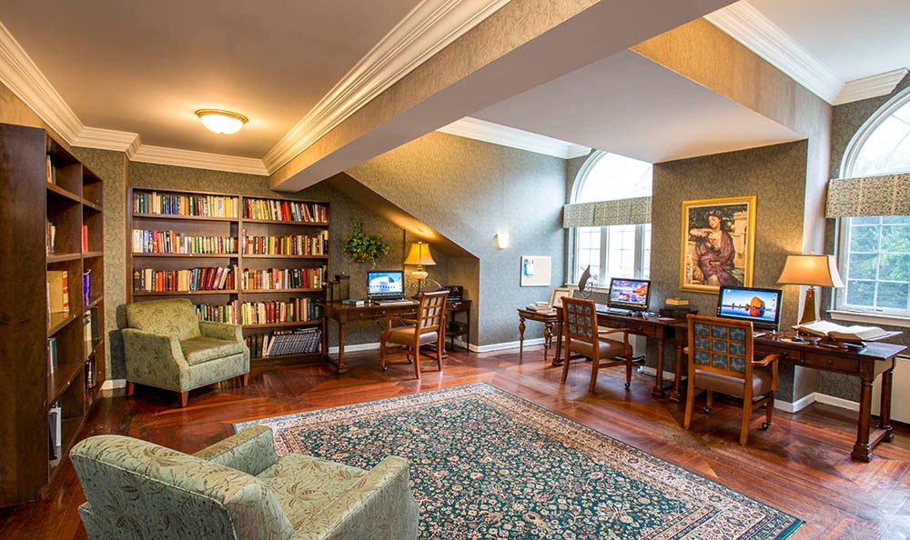 A cozy library reading room with bookshelves, computers, and comfortable seating.