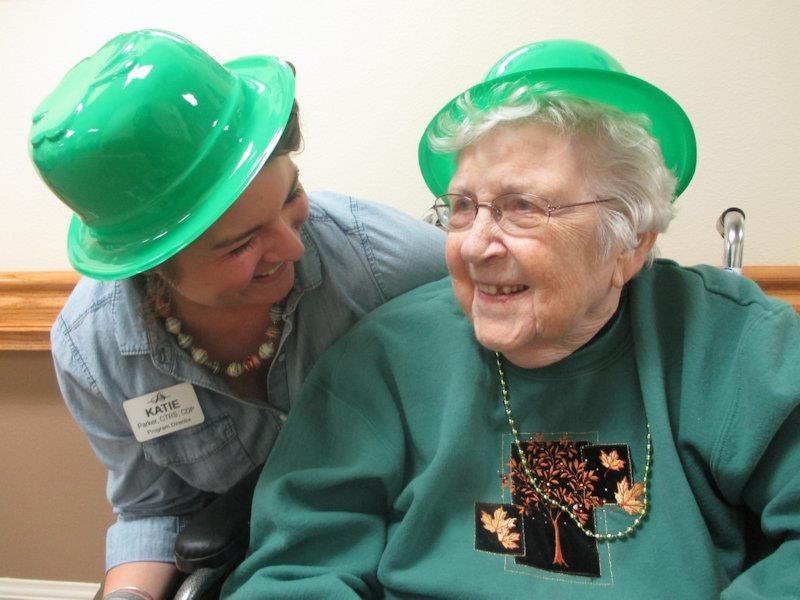 Two women wearing green hats share a joyful moment together.