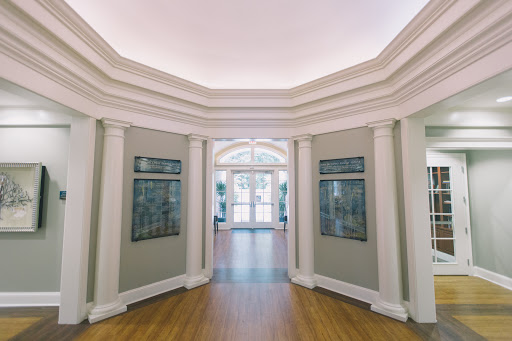 A beautifully designed interior hallway featuring elegant columns and artwork along the walls, leading to a bright entrance.