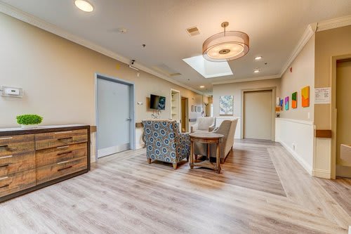A modern living room with comfortable seating, wooden flooring, and a skylight.