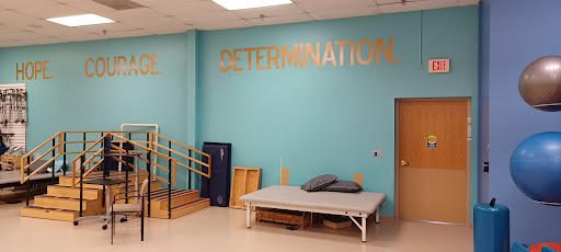 A bright therapy room featuring the word 'DETERMINATION' prominently displayed on the wall, symbolizing motivation and strength in rehabilitation.
