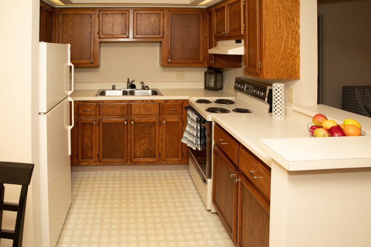 A kitchen with wooden cabinets, a stovetop, and a fridge.
