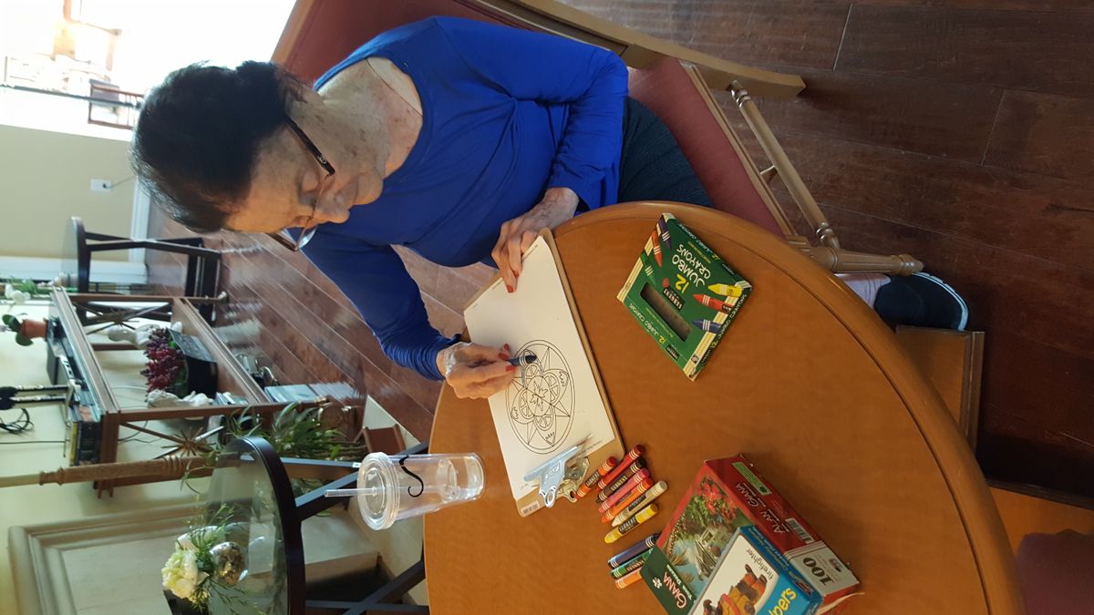 An individual engaged in coloring with crayons at a table.