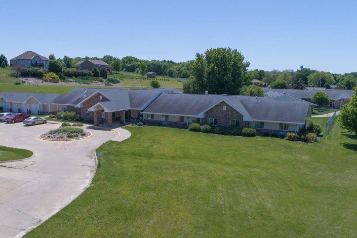 Aerial view of a large suburban house with a vast lawn and driveway.