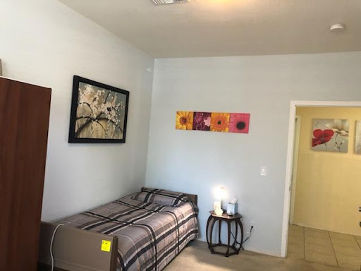 A cozy and well-decorated bedroom featuring a single bed, artwork on the walls, and a nightstand.