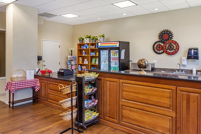 A cozy reception area featuring a snack counter with a vending machine, wooden cabinets, and a merchandise display stand.