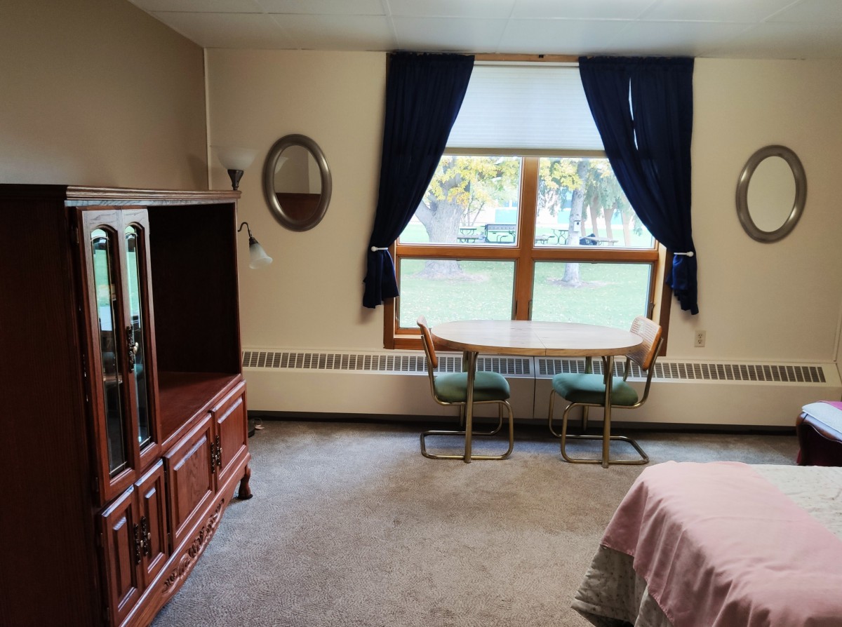A cozy living room with a table and chairs by the window, complemented by dark curtains.