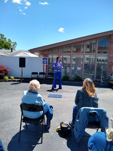 A speaker addresses an audience during an outdoor event, featuring clear blue skies and a vibrant atmosphere.