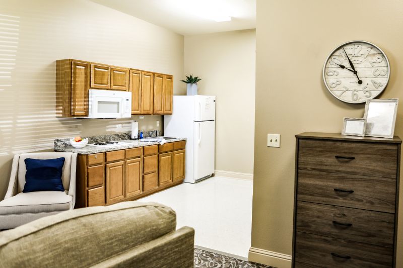 A modern kitchen in an apartment with wooden cabinets, a white refrigerator, and a microwave.