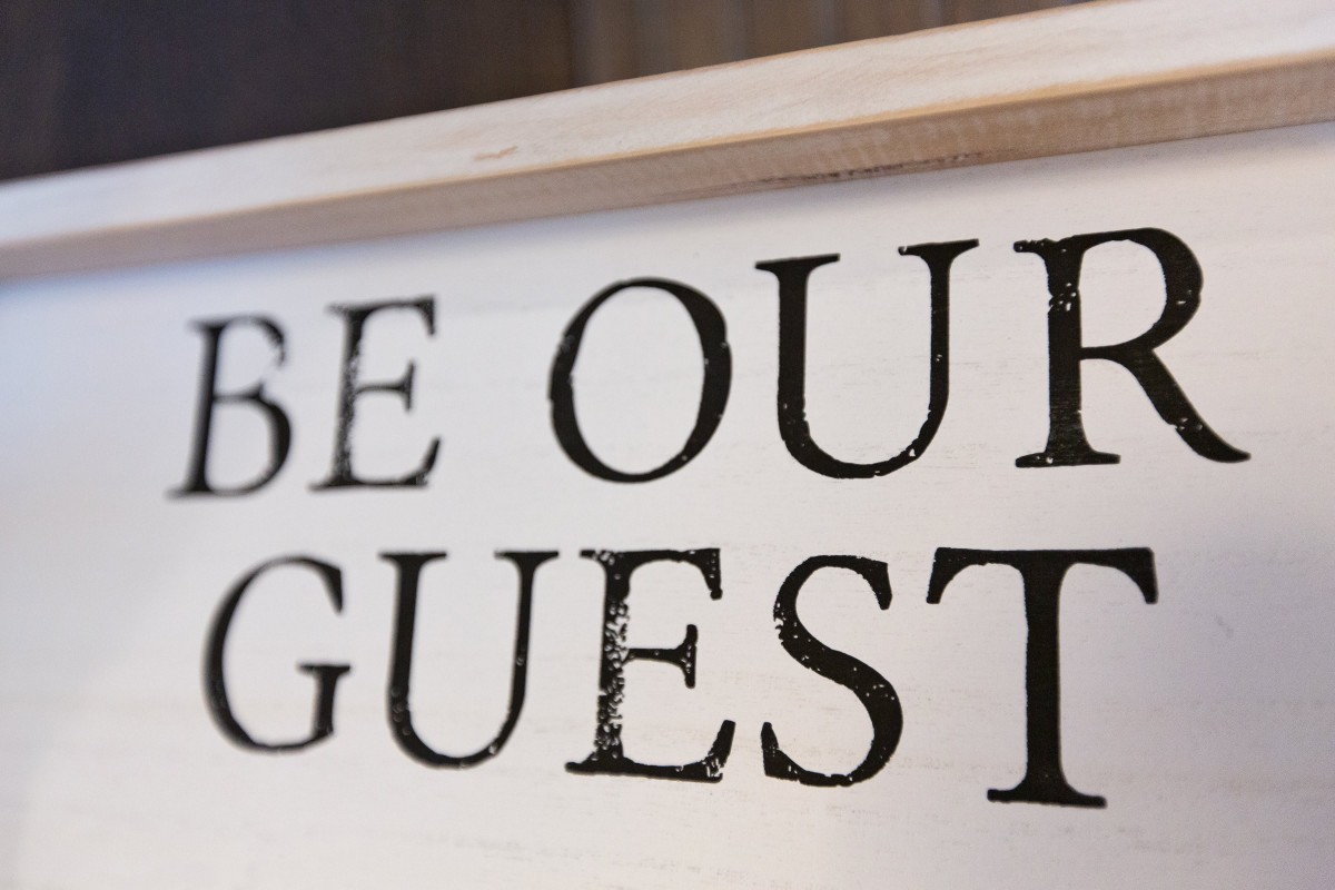 A decorative sign with the phrase 'BE OUR GUEST' written on it.