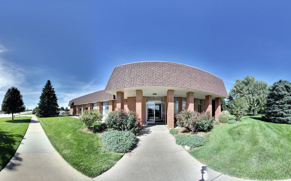 A commercial building with a brick facade and well-maintained landscaping on a sunny day.