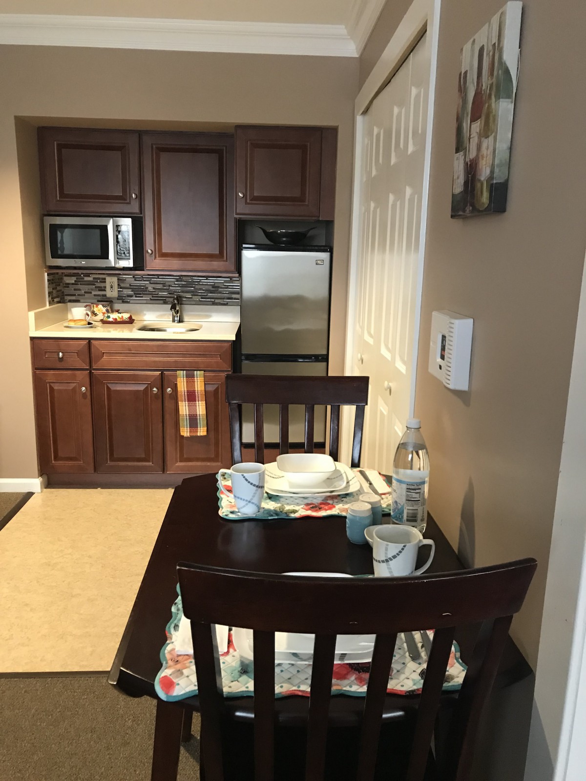 A compact kitchen area with a small dining table set for two, featuring wooden cabinets.