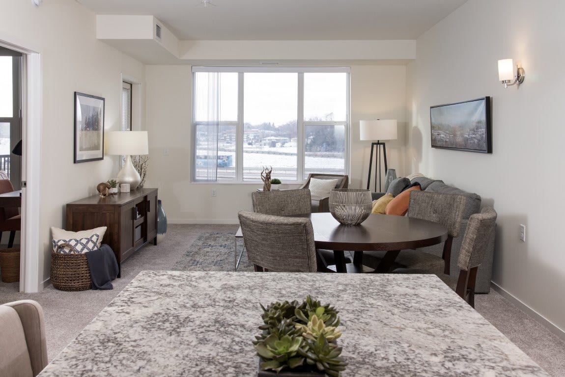 A cozy living room with modern decor featuring a sofa, table, and large window.